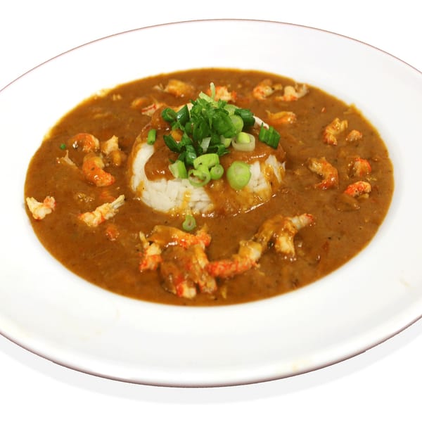 Crawfish etouffee with white rice and green onions on a white plate.