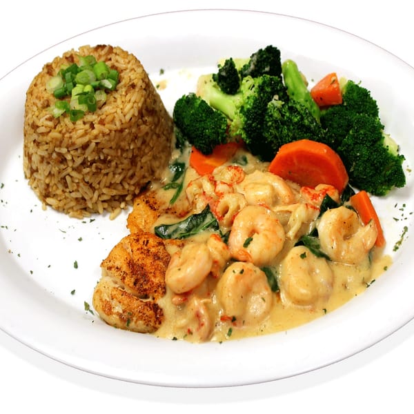 Plate with brown rice, creamy shrimp and crawfish, and steamed broccoli and carrots.